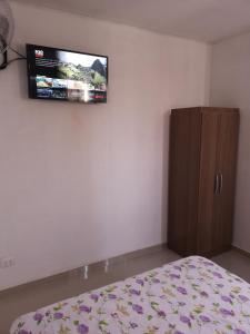 a bedroom with a bed and a tv on the wall at Hospedaje Villa Del Sol in Ica