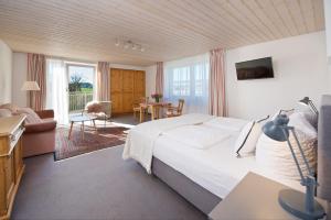 ein Schlafzimmer mit einem großen Bett, einem Tisch und Stühlen in der Unterkunft Landhotel Herzberger garni Zimmer & Ferienwohnungen in Scheidegg