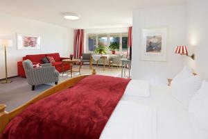 um quarto com uma cama grande e uma sala de estar em Landhotel Herzberger garni Zimmer & Ferienwohnungen em Scheidegg