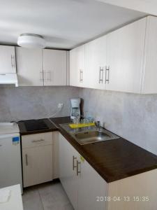 a kitchen with a sink and white cabinets at Cozy Apartment With Side View of Acropolis in Athens