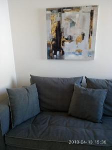 a couch with pillows in a living room with a painting at Cozy Apartment With Side View of Acropolis in Athens