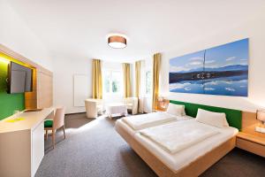 ペルトシャッハ・アム・ヴェルターゼーにあるStrandhotel Kärntnerhofのベッドルーム(ベッド1台、デスク、テレビ付)