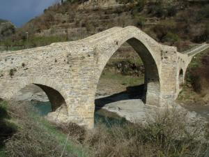 
a bridge over a river with a stone wall at Hotel Cotiella in Campo
