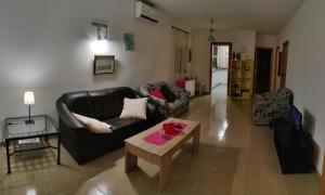 Sala de estar con sofá de cuero negro y mesa de centro en Bungalow, en Denia