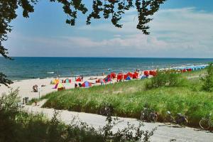 a beach with umbrellas and people on the beach at Aparthotel HAUS USEDOM in Kolpinsee