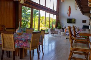 ein Esszimmer mit einem Tisch, Stühlen und Fenstern in der Unterkunft Casa das Acácias in Praia do Forte