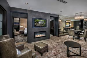 a living room with a fireplace and a dining room at The Hotel at the University of Maryland in College Park