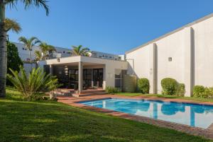 a house with a swimming pool in front of a building at Sands Beach Breaks Umdloti Beach View in Umdloti