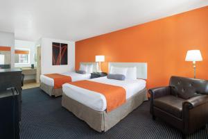 ein Hotelzimmer mit 2 Betten und einem Stuhl in der Unterkunft Howard Johnson by Wyndham Holbrook in Holbrook