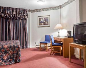 Cette chambre comprend un lit, un bureau et une télévision. dans l'établissement Econo Lodge by the Falls, à Niagara Falls