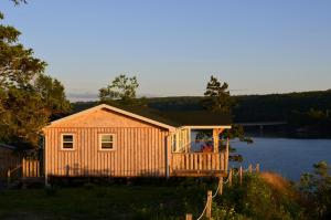 a wooden cabin with a porch on a lake at Still Point Lodge in Deep Brook