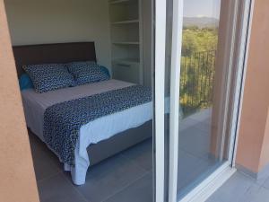 1 dormitorio con cama y vistas a un balcón en SARL valinco locations en Olmeto