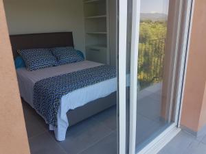 a bedroom with a bed and a view of a balcony at SARL valinco locations in Olmeto