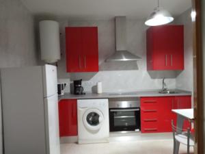 una cucina con armadi rossi e una lavatrice di Apartamento Turistico La Victoria a Trujillo