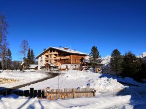 una baita di tronchi nella neve con una recinzione di Chalet Frapes a San Martino in Badia