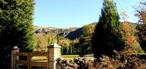 a wooden gate with a fence and trees and mountains at Casa Natura Gerês in Campo do Gerês