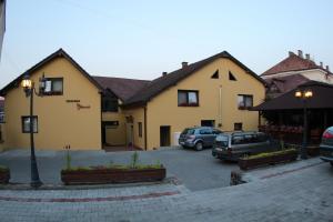 un bâtiment avec des voitures garées dans un parking dans l'établissement Pensiunea Blanca, à Reghin