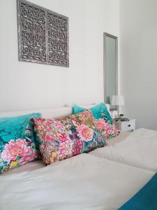 a white bed with colorful pillows on top of it at Paradise Apartman in Miskolc