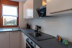eine Küche mit weißen Schränken, einem Waschbecken und einem Fenster in der Unterkunft FeWo Litzendorf in Litzendorf