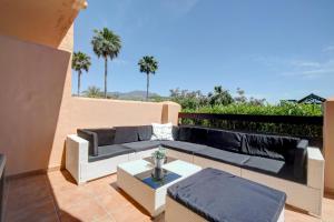 a patio with a couch and a table on a balcony at Casares del Sol Ground Floor Apartment in Casares