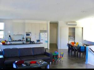 ein Wohnzimmer und eine Küche mit einem Sofa und einem Tisch in der Unterkunft Bundalong Waterfront in Bundalong