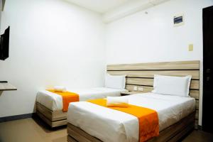 two beds in a hotel room with orange and white at Travelbee Fuente Inn in Cebu City