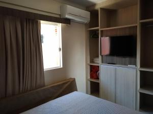 um quarto com uma cama, uma TV e uma janela em Park L'acqua di roma - Cozinha completa em Caldas Novas