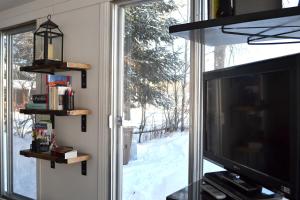 a living room with a television and a window at Les 4 chalets - Le 605 in Lac-Saint-Paul