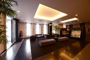 eine Lobby mit einem Wartebereich mit Sofas und einem TV in der Unterkunft Hotel Route Inn Grand Ueda Ekimae in Ueda