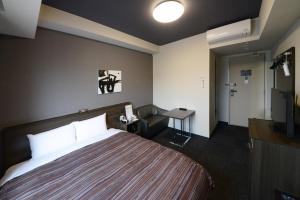 上田市にあるホテルルートイングランド上田駅前のベッドとデスクが備わるホテルルームです。