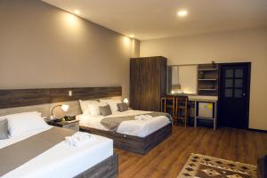 a hotel room with two beds and a kitchen at Hotel Raymipampa in Cuenca