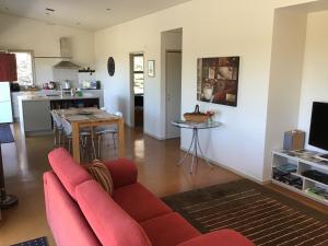 een woonkamer met een rode bank en een keuken bij Nikau’s on Palmer in Foxton Beach +14 foto's