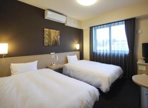 a hotel room with two beds and a window at Hotel Route Inn Kesennuma Chuo Inter in Kesennuma