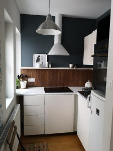 a kitchen with white cabinets and a black wall at Przytulna Kawalerka w Kamienicy in Olsztyn