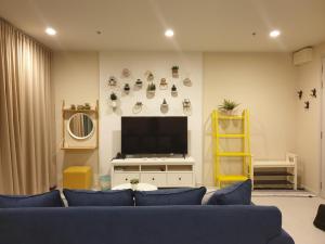 sala de estar con sofá azul y TV en Blu Condo (Chaam - Huahin) en Cha Am