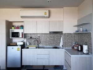 a kitchen with white cabinets and a white refrigerator at Blu Condo (Chaam - Huahin) in Cha Am