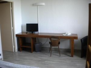 a desk with a computer and a chair in a room at Hôtel La Randonnée in Nasbinals