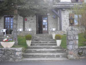 una casa de piedra con escaleras que conducen a una puerta en Hôtel La Randonnée, en Nasbinals