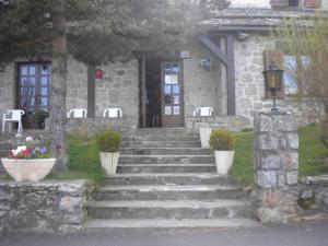 a stone house with stairs leading to a door at Hôtel La Randonnée in Nasbinals