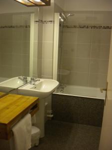 a bathroom with a sink and a toilet and a tub at Hôtel La Randonnée in Nasbinals