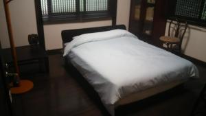 a bedroom with a bed with white sheets and a window at Guest House Koundo in Nikko