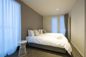 a bedroom with a large white bed with blue curtains at Yotei Yama House in Niseko