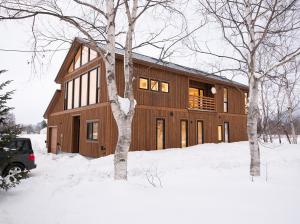 una gran casa de madera en la nieve con árboles en Yotei Yama House, en Kutchan