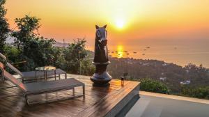 a balcony with a view of the ocean and a sunset at Naroua Villas in Ko Tao