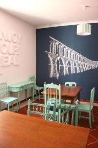 a dining room with tables and chairs and a wall with a painting at Hostel 2300 Thomar in Tomar