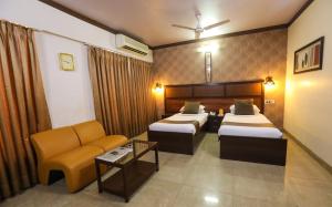 a hotel room with two beds and a couch at Jyoti Dwelling Hotel in Mumbai