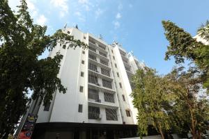 ein weißes Gebäude mit Bäumen davor in der Unterkunft Jyoti Dwelling Hotel in Mumbai