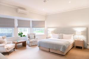 a white bedroom with a bed and a chair at Cape Lodge in Yallingup