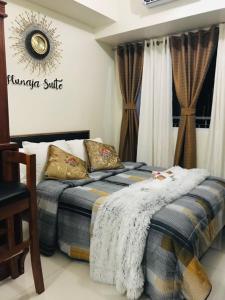 1 dormitorio con 1 cama con manta y almohadas en Hunaja's Home at Wind Residences TAGAYTAY en Tagaytay