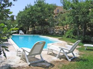 Duas espreguiçadeiras e uma piscina com uma mesa e duas cadeiras em Les Restanques em Goult